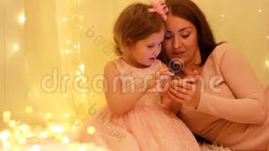 小女孩和他妈妈在手机上玩游戏。 宝宝和妈妈在智能手机上看视频